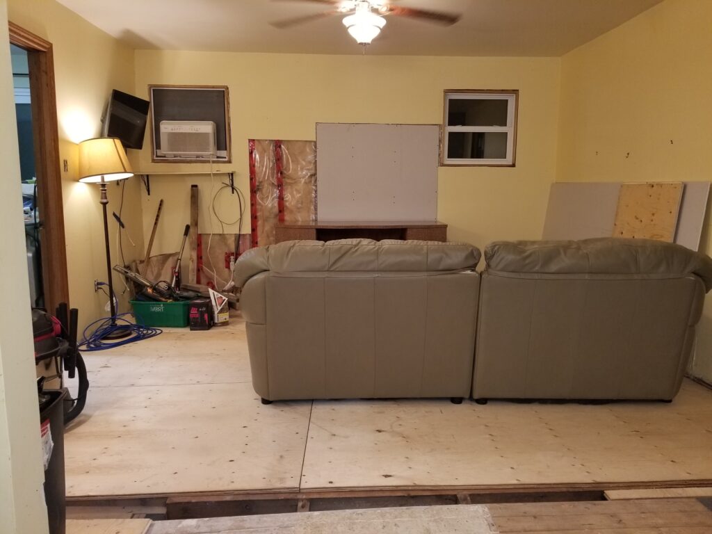 Room with less clutter and plywood covering majority of floor